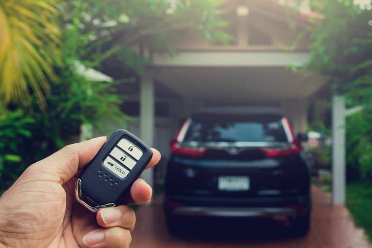 A remote car keys and black car in the house, Why Is My Remote Start Disabled? [Inc. System Fault]