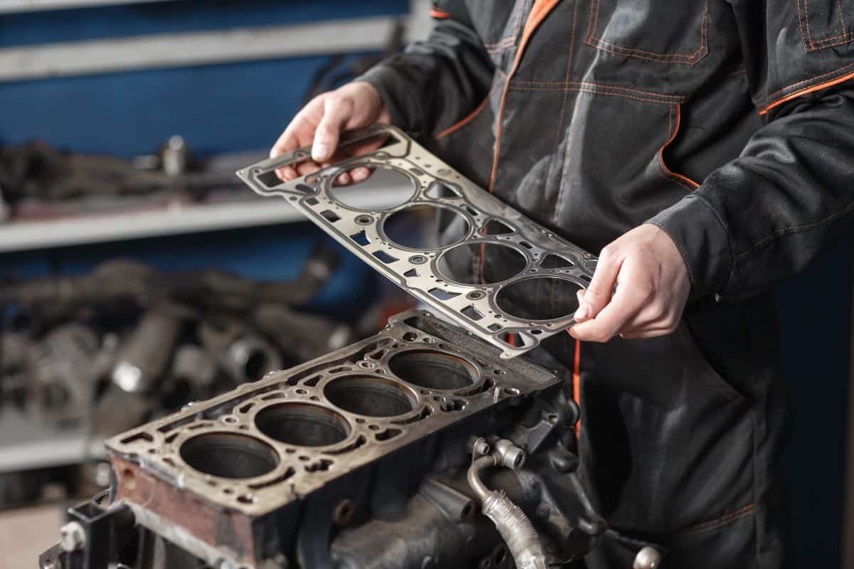 Sealing gasket in hand. The mechanic disassemble block engine vehicle. Engine on a repair stand with piston and connecting rod of automotive technology. Interior of a car repair shop.