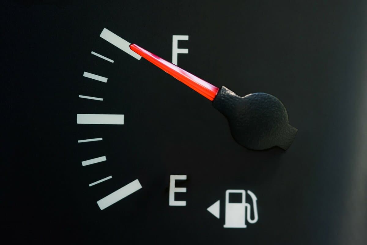 The car's fuel gauge shows a full, close-up, rough black panel.