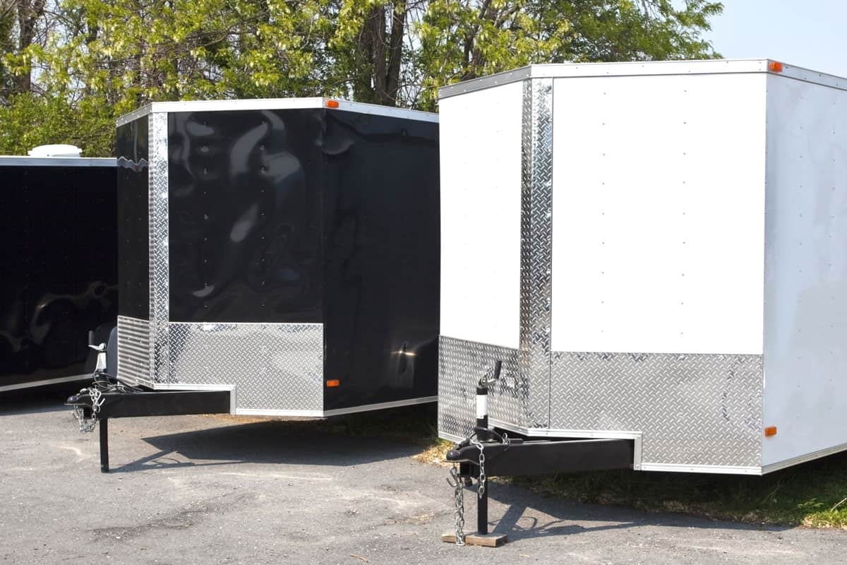 Three black and white transport trailers for sale or rent in a row