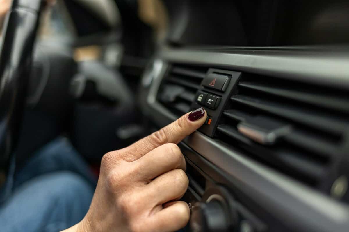 Woman adjusting interior temperature while driving on the road, Female driver is adjusting the air conditioner of the car