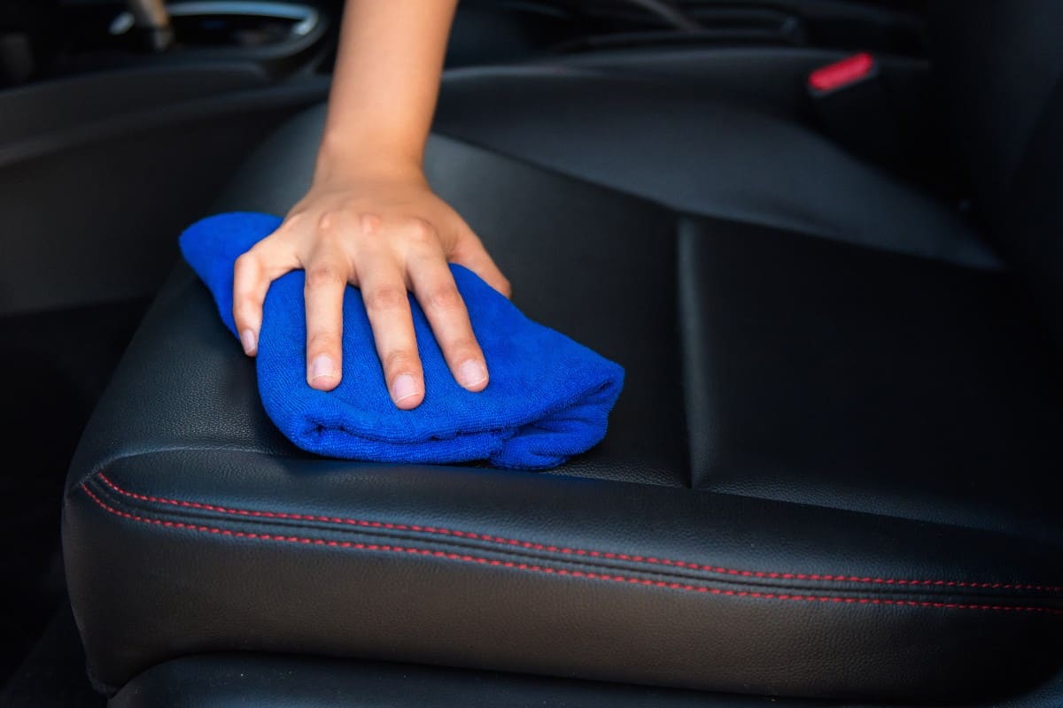 Woman hand is cleaning car seat with microfiber fabric