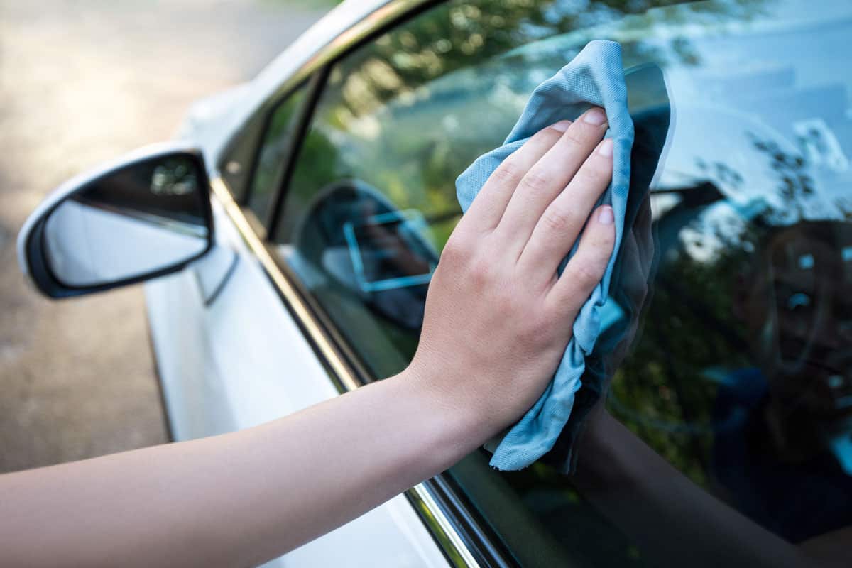 male-hand-cleaning-car-window-blue