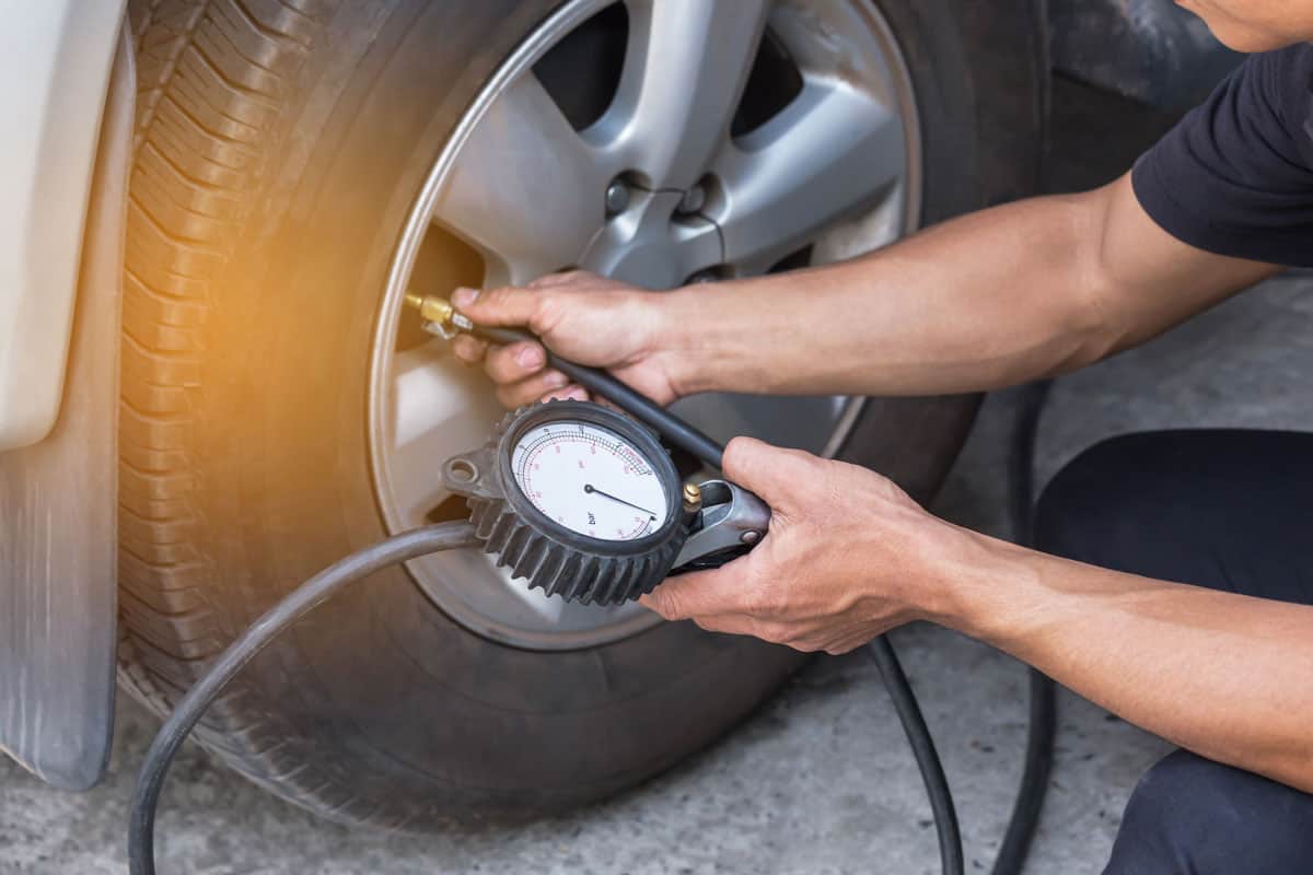 mechanic inflating tire and checking air pressure with gauge pressure in service station