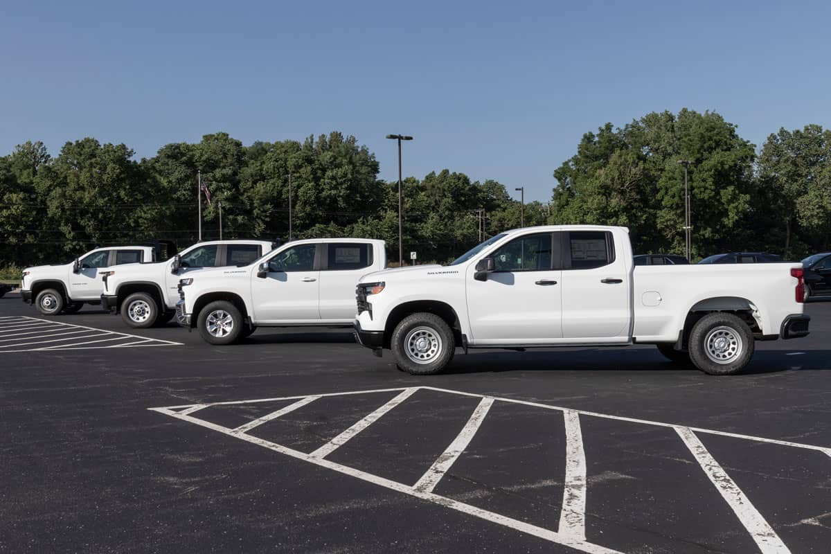 4 white Chevrolet Silverado 3500 pick up trucks on car park