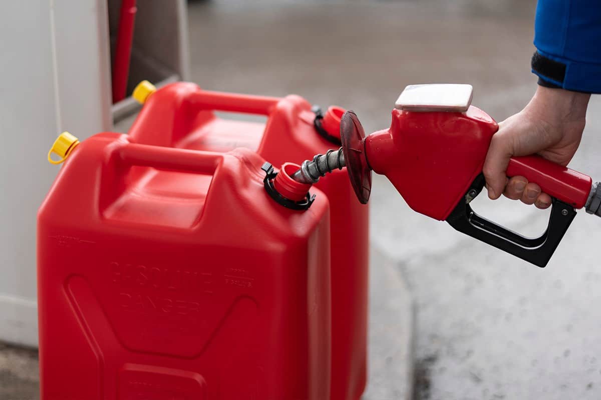 A man fills jerry cans at a gas station