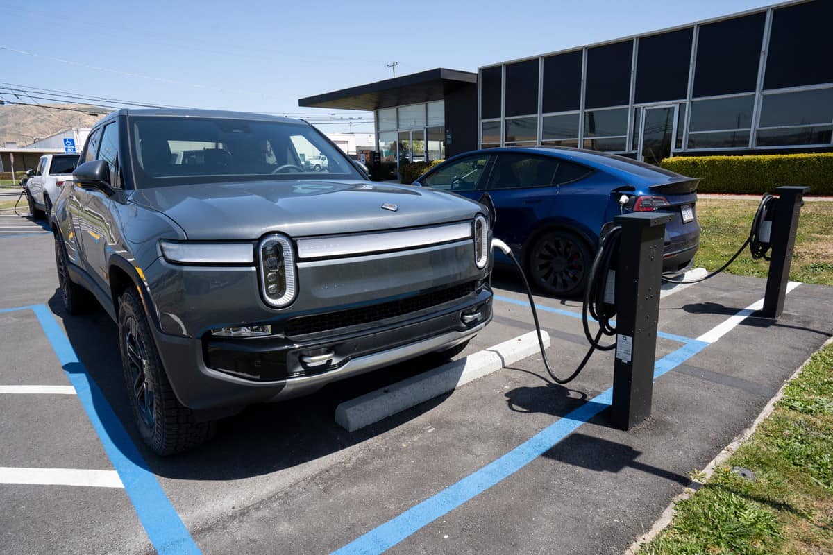 A new Rivian R1T truck and a Tesla Model Y SUV are seen charging at a Rivian service center in South San Francisco, California. 