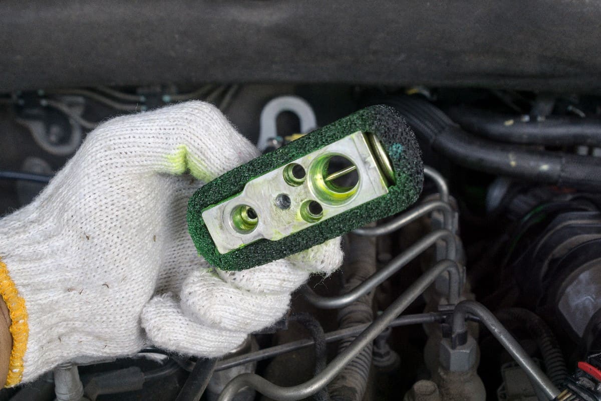 An old expansion valve of a car's air conditioning system with a leaking refrigerant