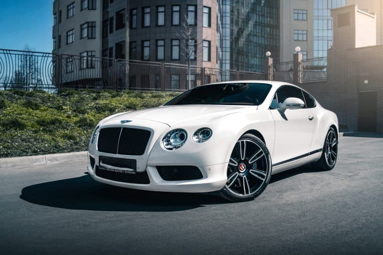 white Bentley Continental GT with building beside it, Why Is My Bentley Continental AC Not Working [3 Possibilities & Fixes]