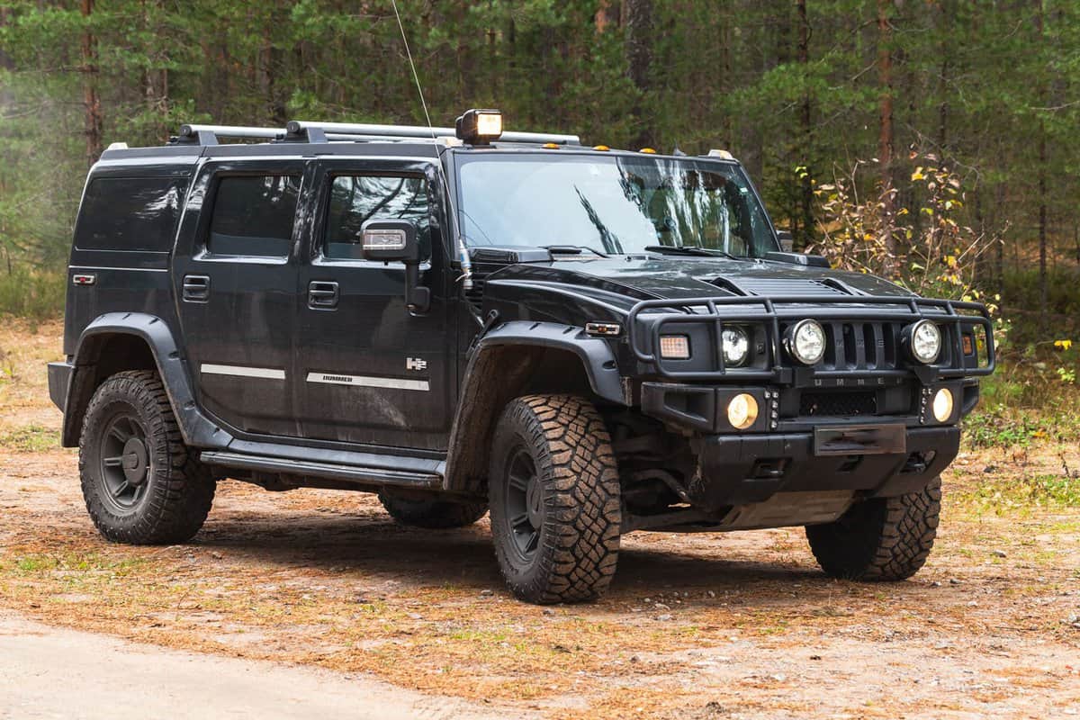 Black Hummer H2 vehicle stands on dirty country road