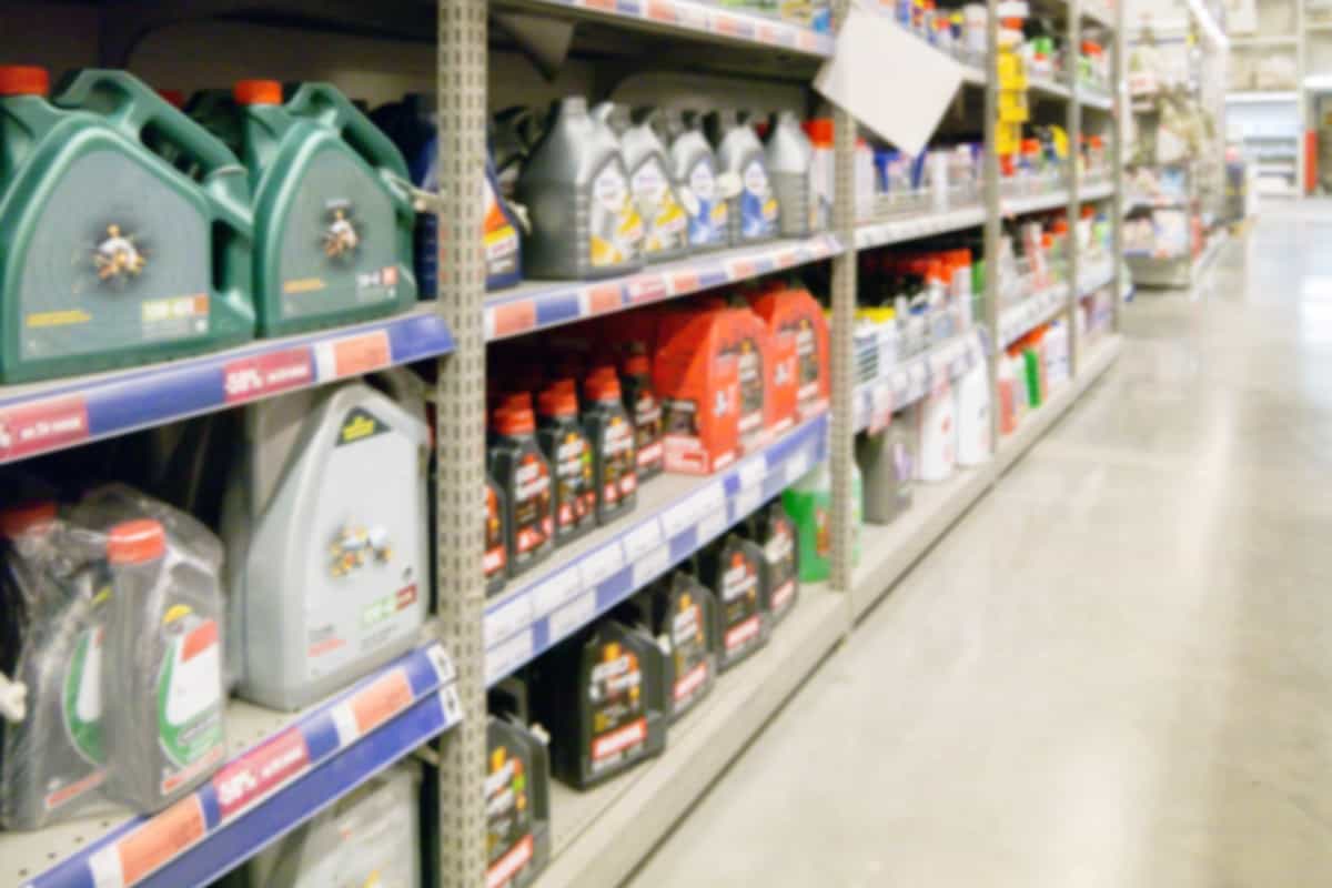Blurred colorful motor oil bottles on shelves in supermarket as background.
