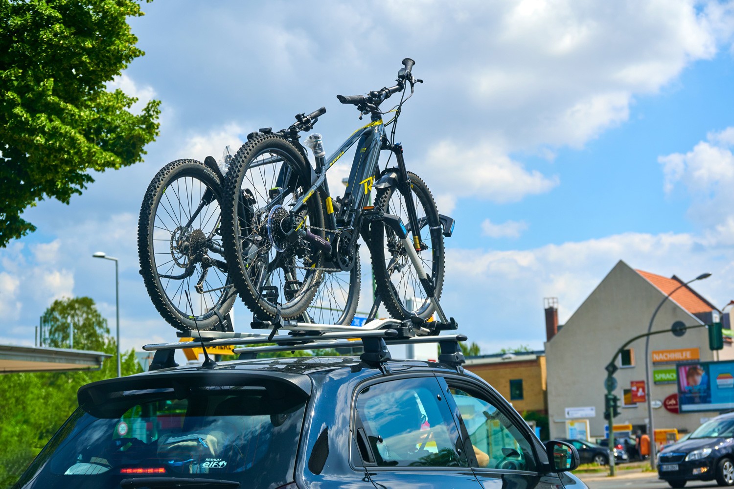 Car with a bike carrier attached on the top and two bicycles mounted on it.