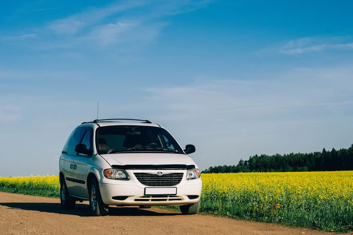 Chrysler Voyager in summer meadow landscape. on the background of yellow field