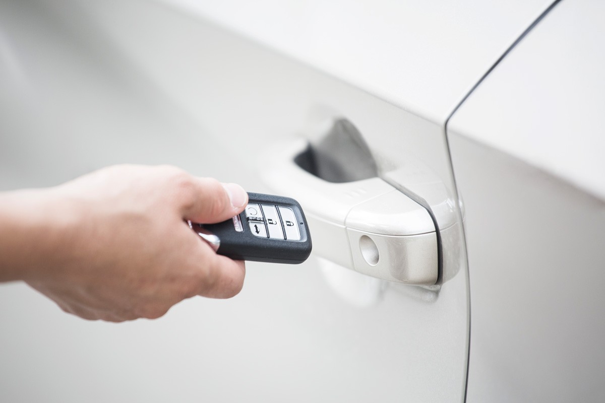 Human hand holding a keyless entry device or key fob to open the new car and start the car.