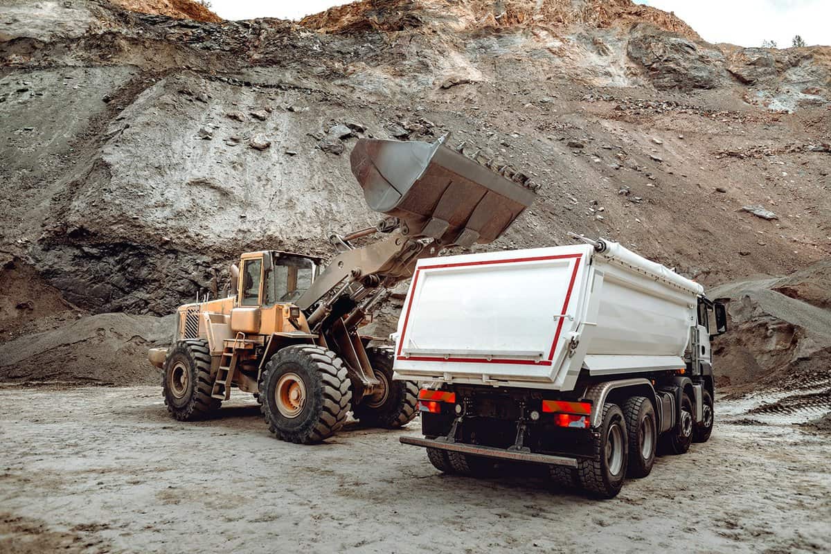 Industrial dumper trucks and wheel loader bulldozer working on highway construction site