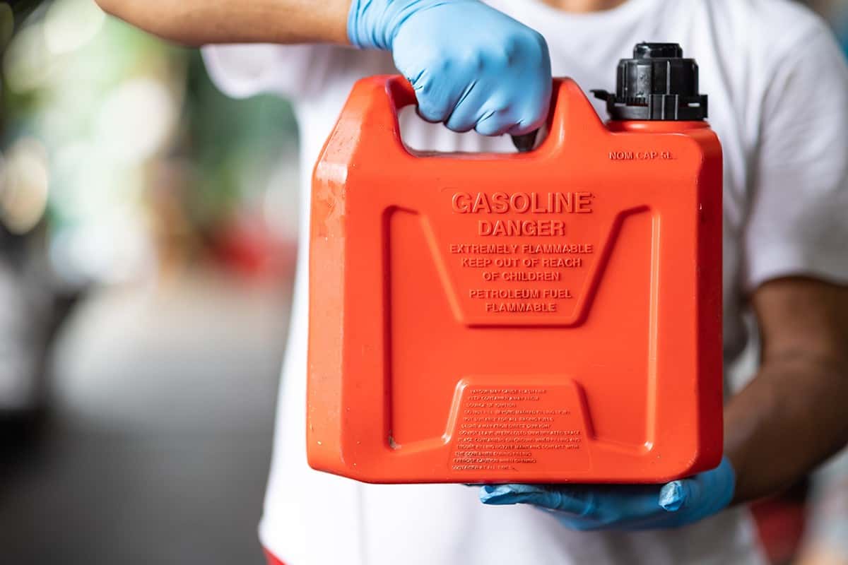 Man handle red plastic fuel gallon flammable material container for refill gasoline car tank