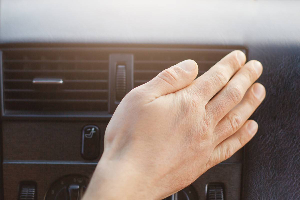Man`s hand on car heater or conditioner, regulates temperature in automobile while drives. 