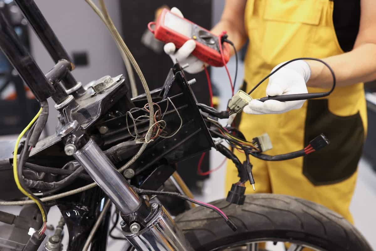 Mechanic using multimeter checks voltage level motorcycle