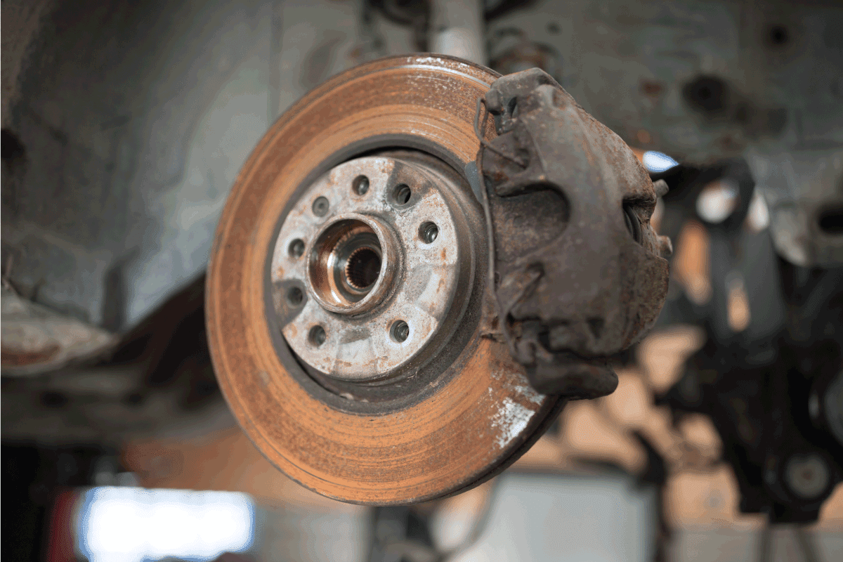 Old and rusty car's suspension parts. Rusted disc brake and caliper on the car