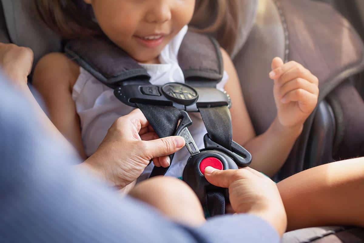 Parent buckling her child's seat belt in the car