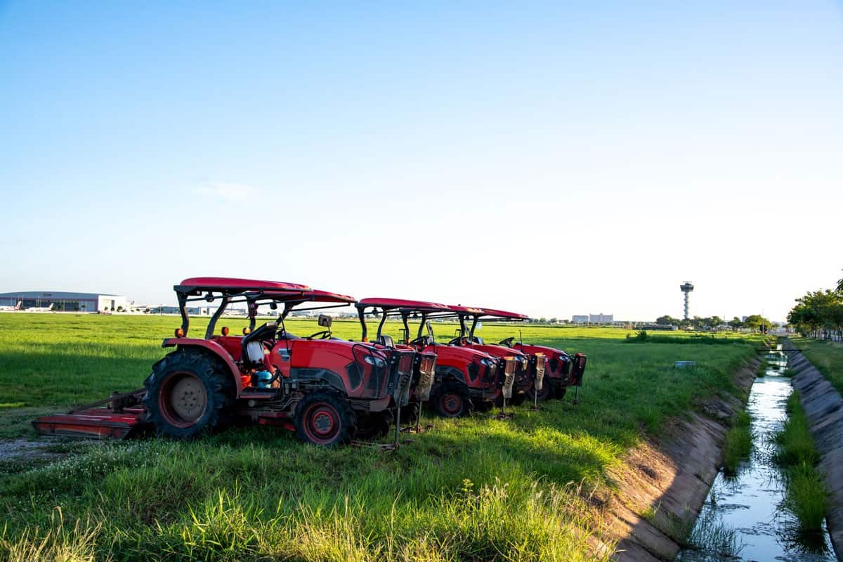 Red tractors parking in a grass field with blue sky background and small stream water