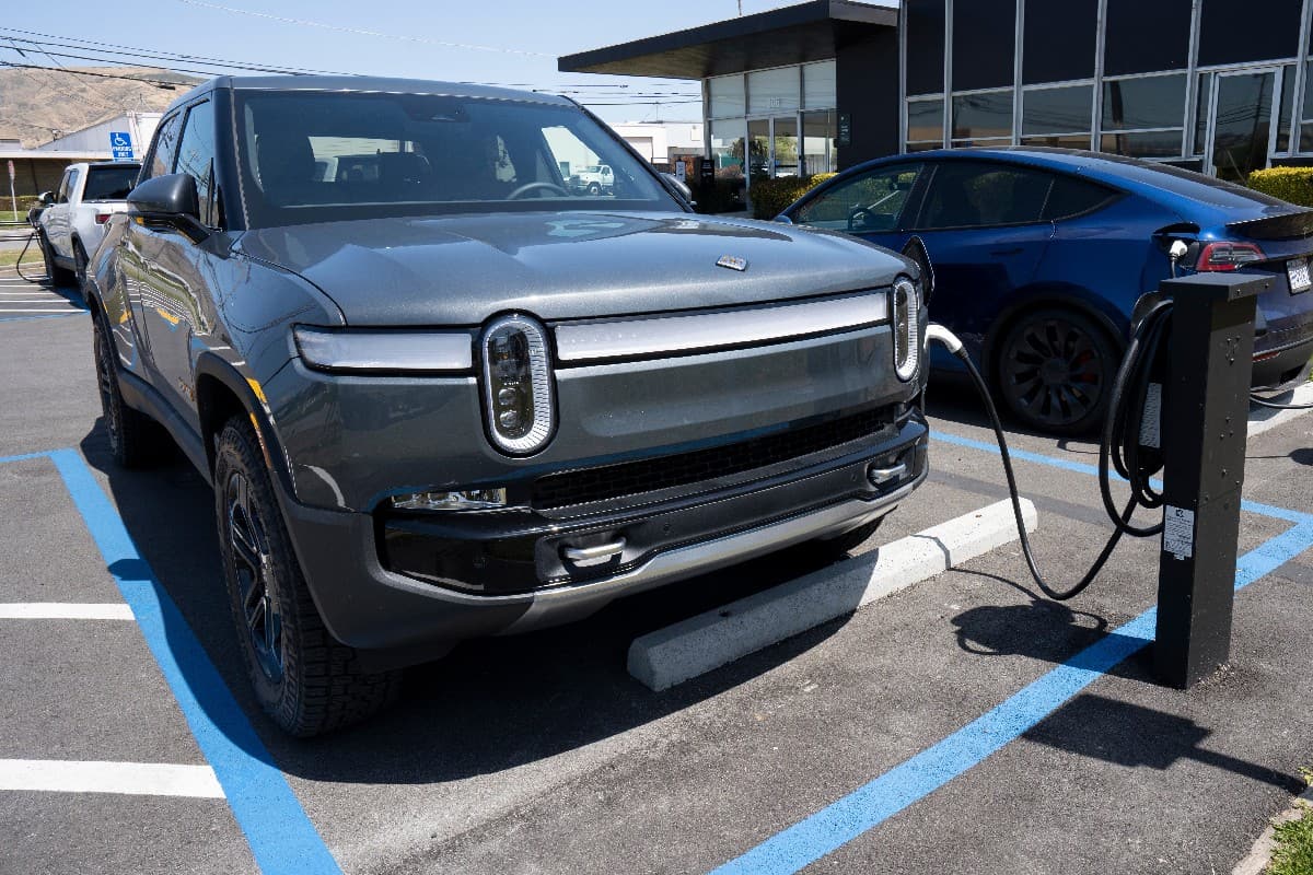 Rivian R1T truck and a Tesla Model Y SUV are seen charging at a Rivian service center