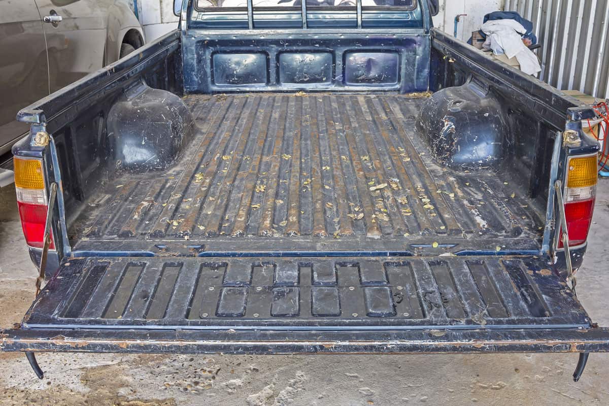 The tailgate of a blue battered eighties Pickup Truck in rear