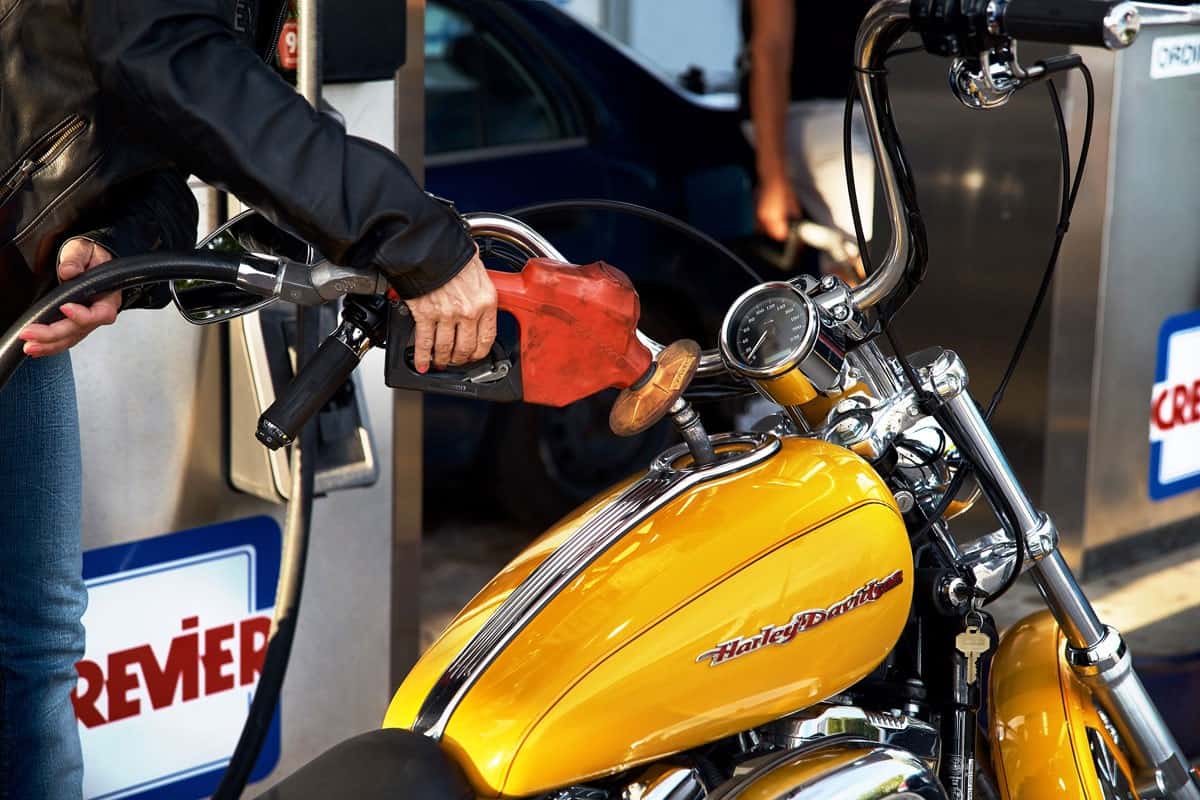Woman hand close up tucking a Harley Davidson motorcycle at a gas station. old gas station in Crevier on the road to Ottawa from Mon