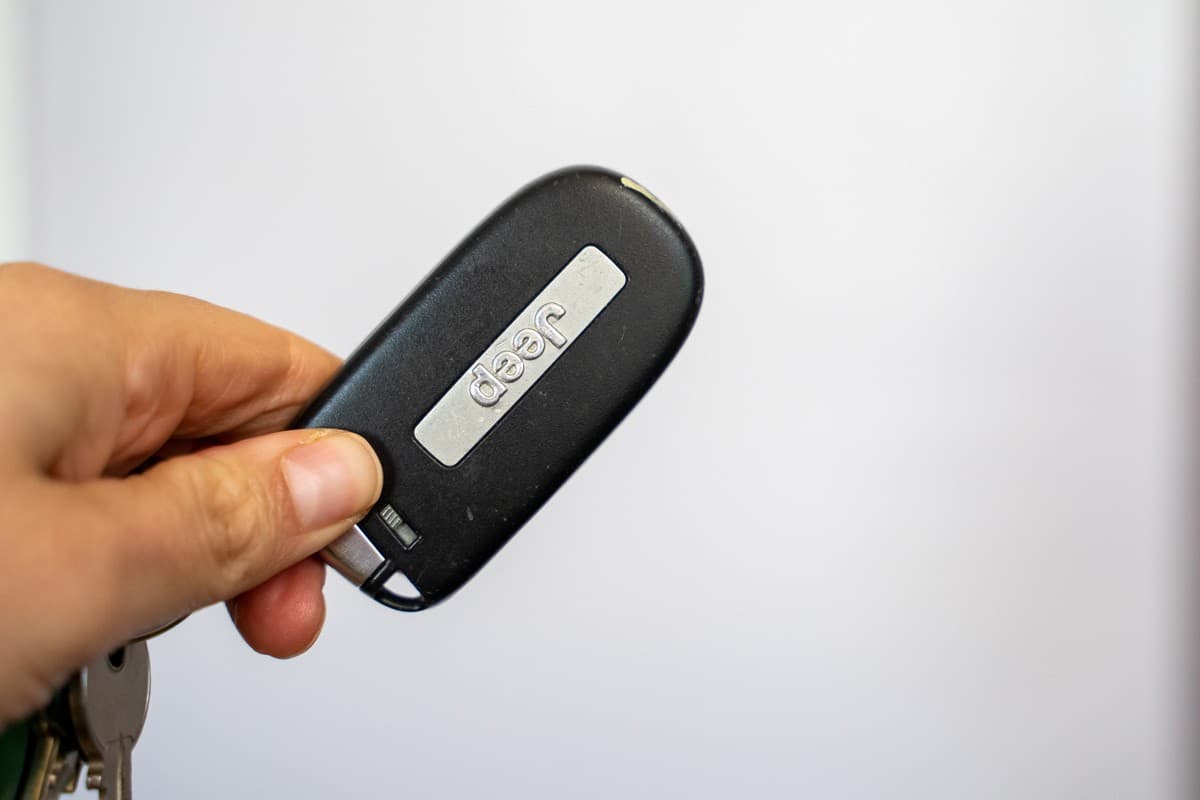 Woman hand holds a Jeep key fob remote for her SUV vehicle
