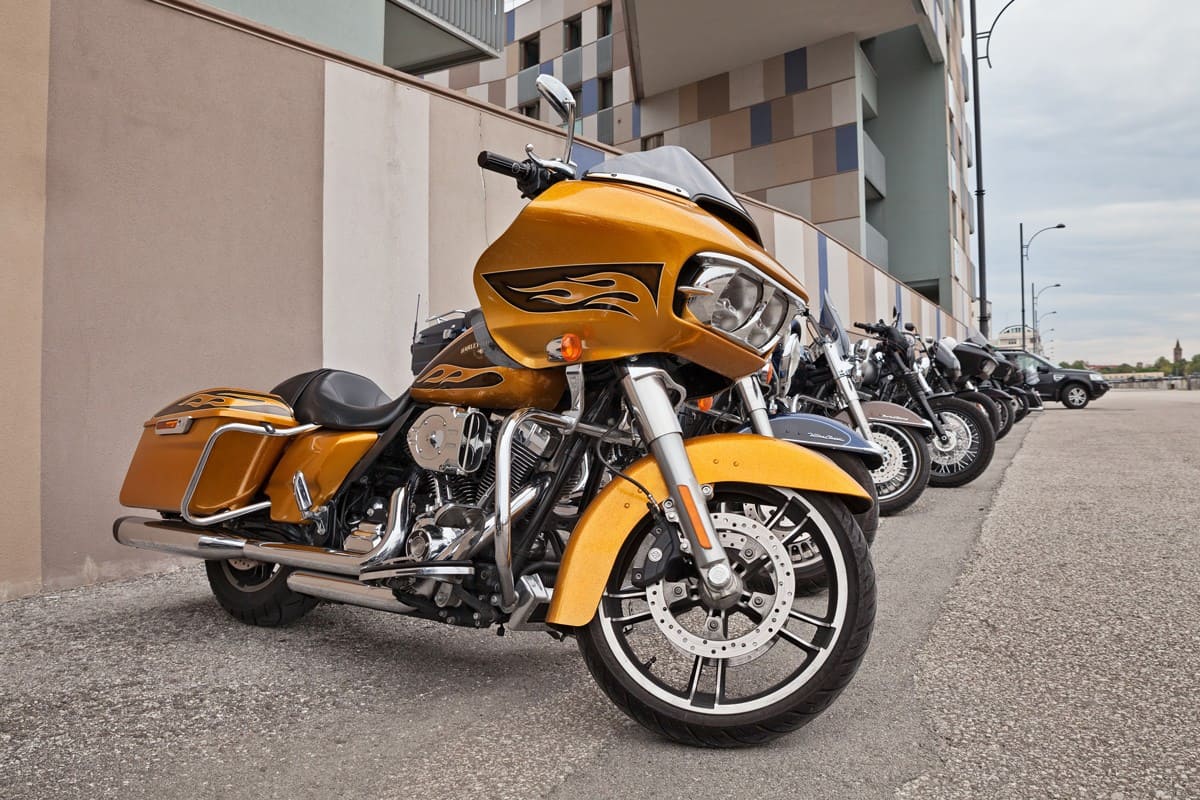 Yellow painted Harley Davidson parked on the side of a building
