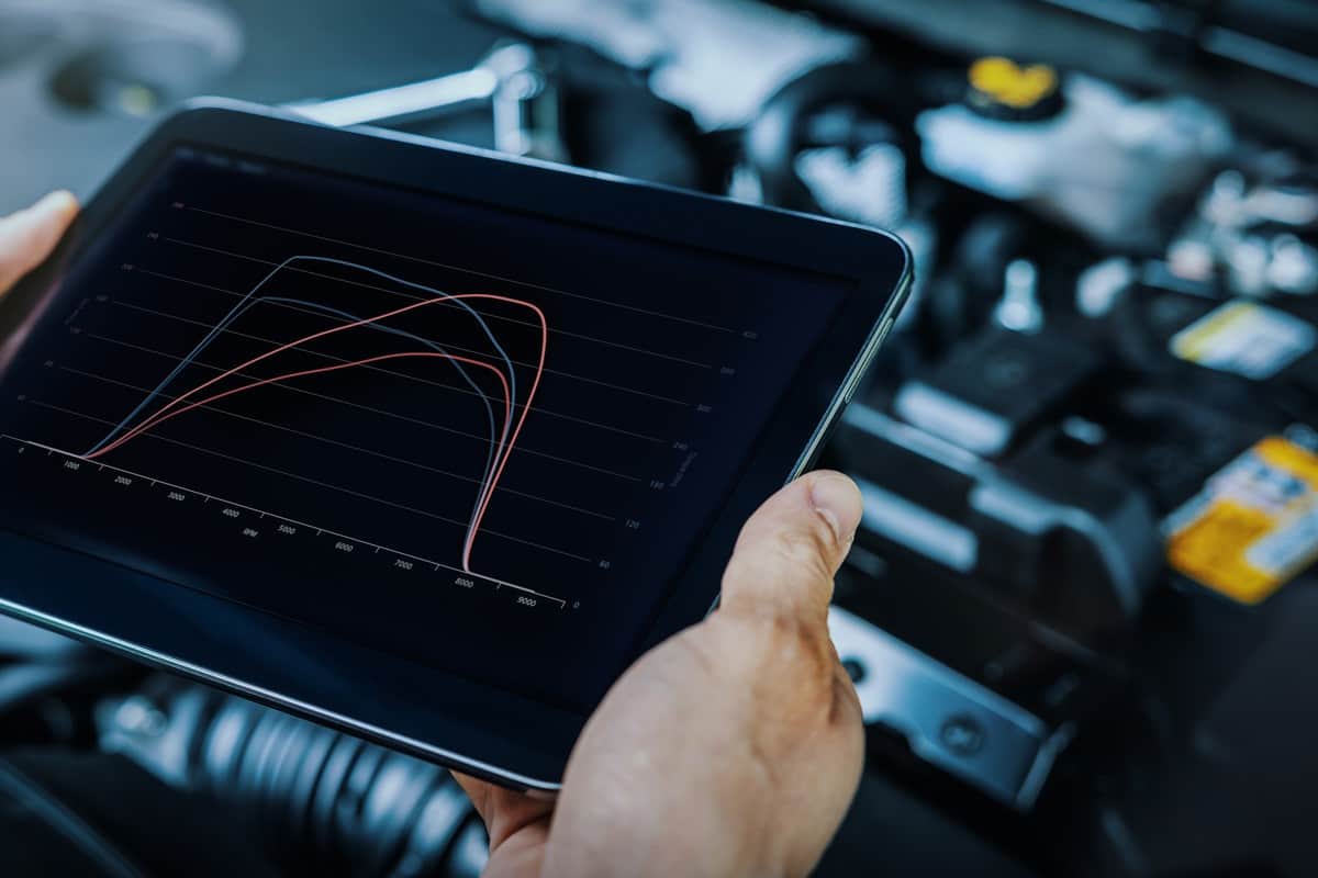 car engine ecu remapping and diagnostics. mechanic using digital tablet to check vehicle performance after chiptuning.