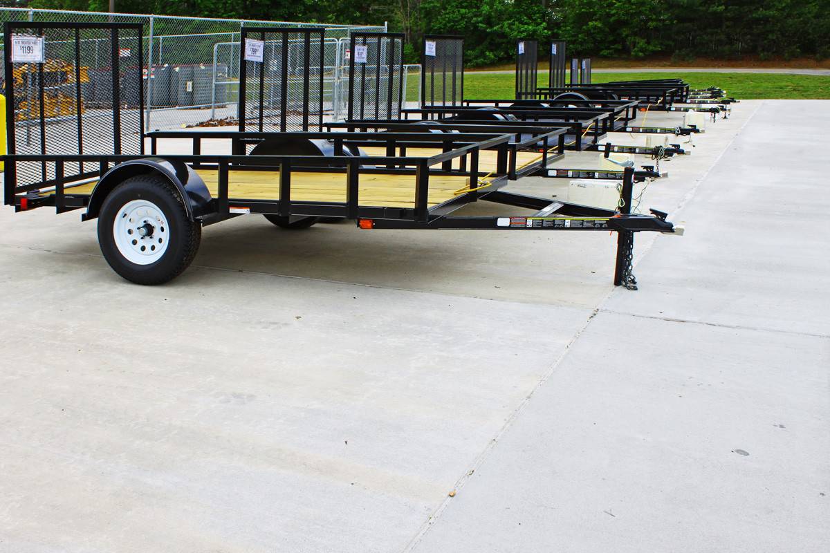 A row of brand new utility trailers lined up and locked together outside for sale with room for your text.