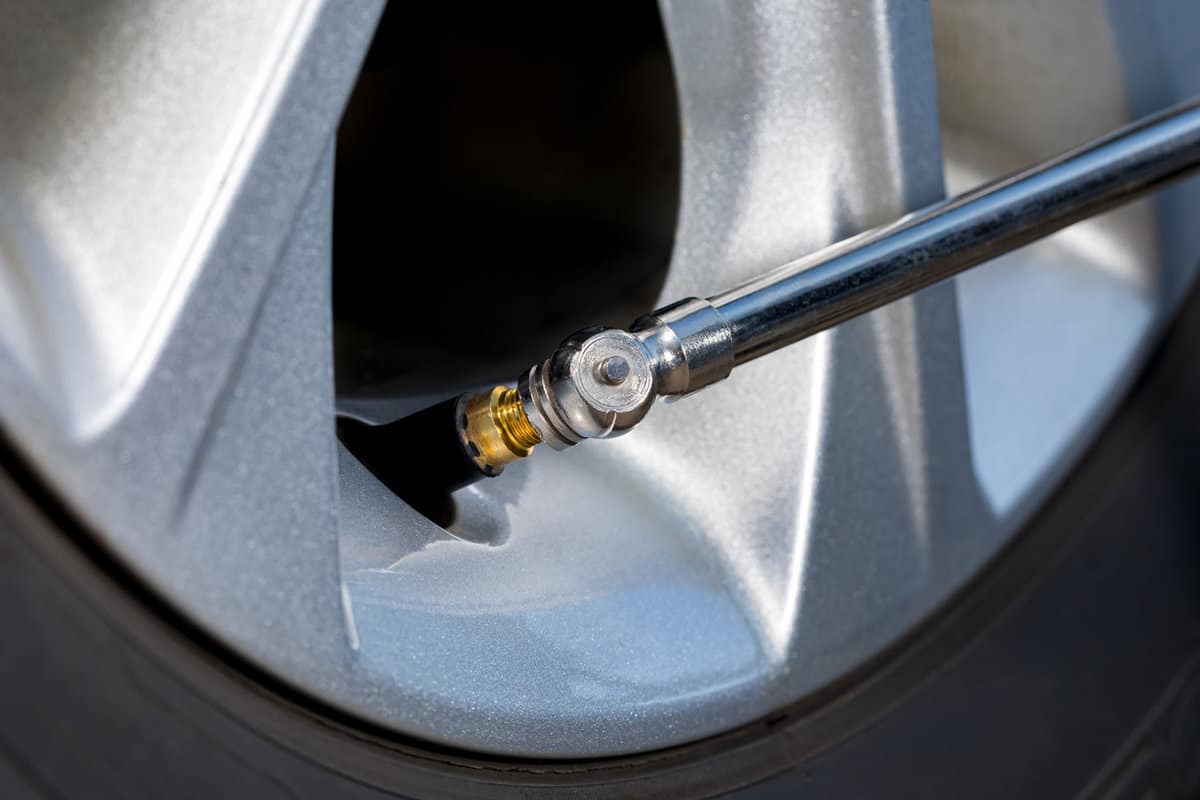 Air pressure gauge on tire valve stem of car wheel. Vehicle safety, tire wear, fuel mileage and winter checkup concept. 