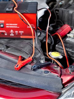 Battery charger and car in an auto repair shop, Can I Use An Extension Cord With A Car Battery Charger?