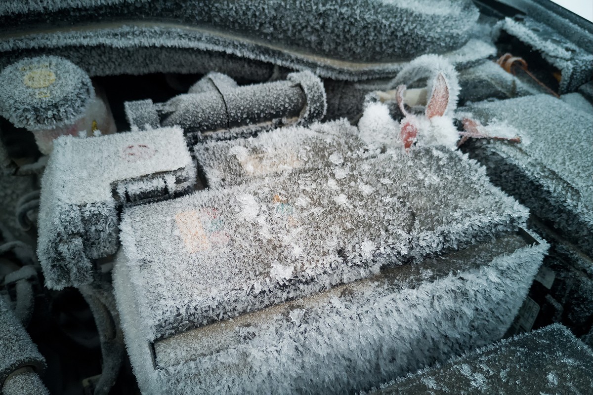 Car battery covered in snow and ice