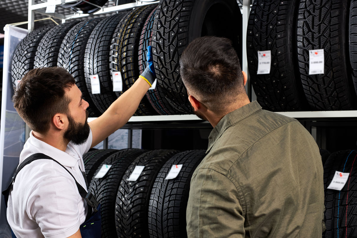 Car mechanic and client choosing perfect tire size for car
