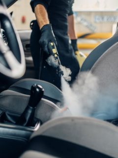 Carwash, worker cleans seats with steam cleaner, Can Auto Detailing Remove Mold?