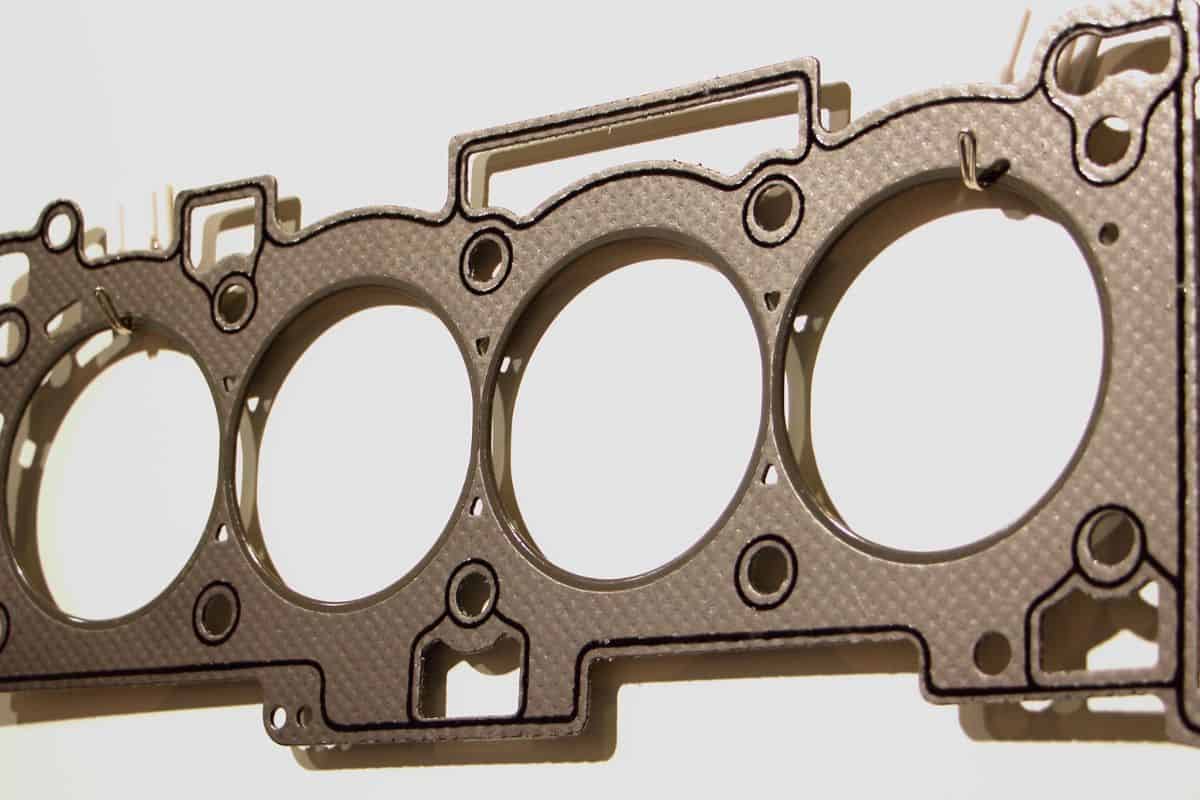 Closeup new engine cylinder head gasket with metal rings and sealing stripe, four cylinder car motor repair parts