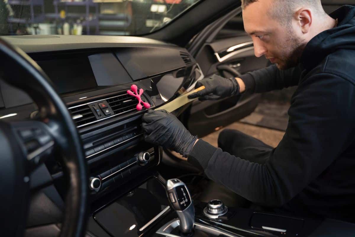 Detailing worker pasting protective tape on the car interior trim before polishing