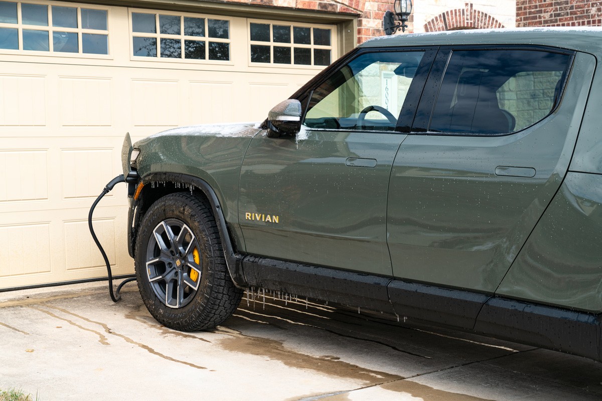 Frozen Winter Storm freezes the Rivian R1T Electric Pick Up Truck with Ice cycles and snow covered EV while on Home Charger