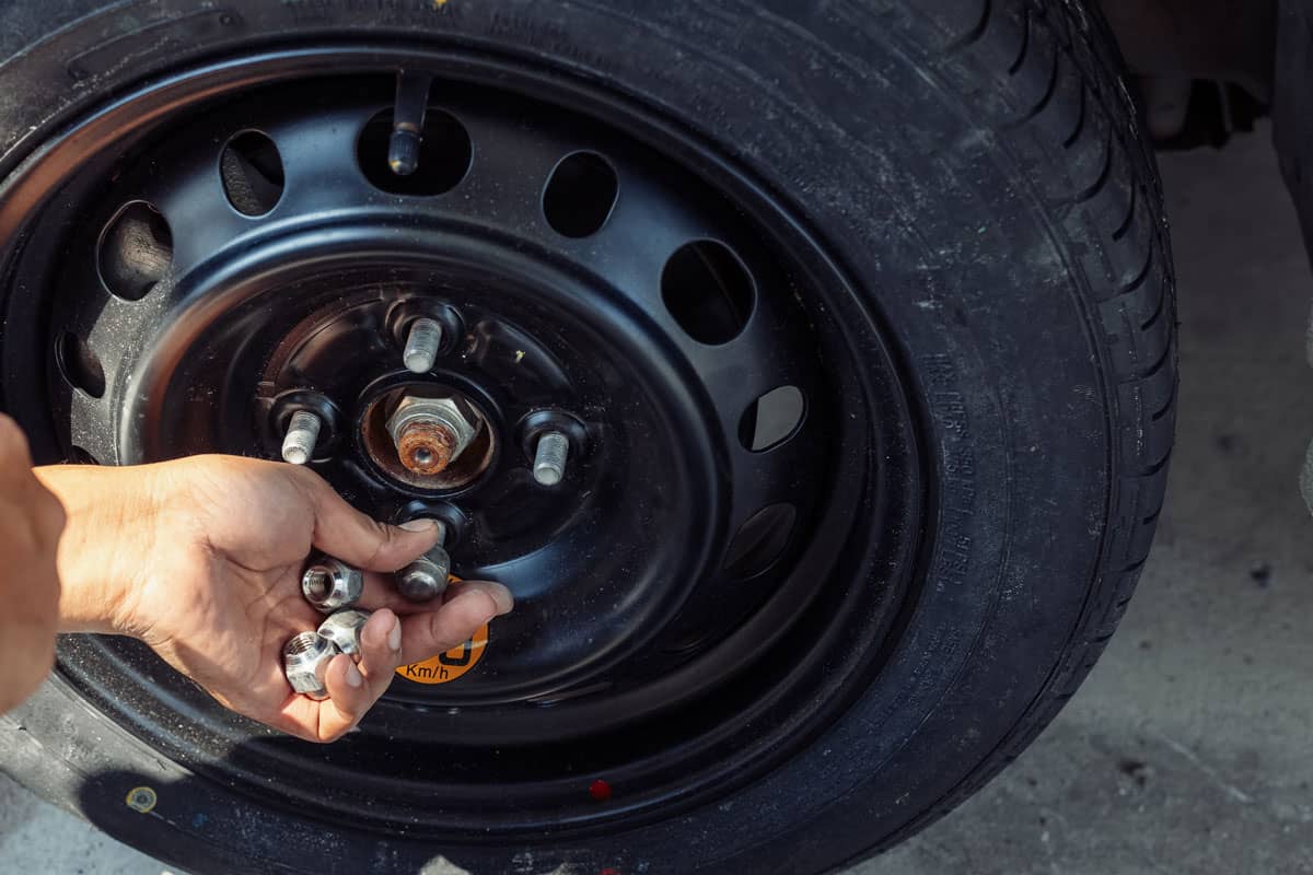 Hands of mechanic pick up the nut of car wheel.Change a flat car tire at car park with Tire maint