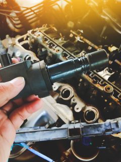 Ignition coil for spark plug of the car ignition system in the auto mechanic hand with a car engine blurred background in the repair garage, How Often Should Ignition Coils Be Replaced