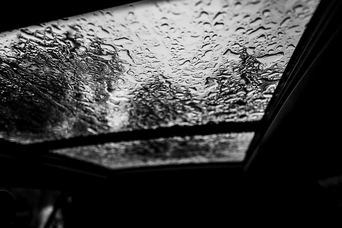 Inside a vehicle looking up to a sunroof with water droplets