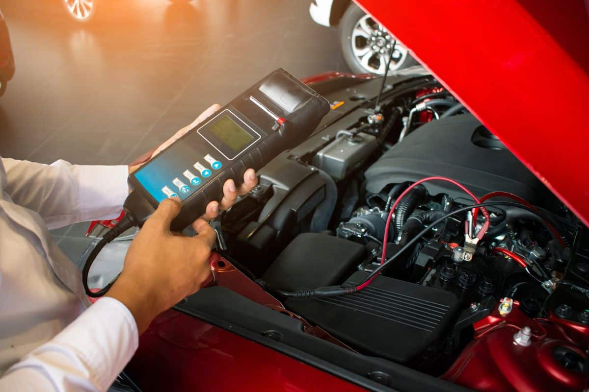 Man holding battery capacity tester voltmeter for service maintenance of industrial to engine repair