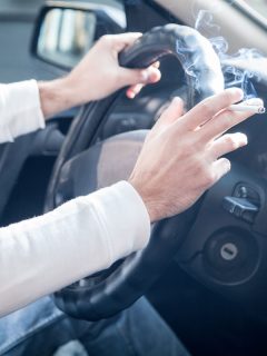 Man smoking a cigarette at the wheel of a car, Driving and smoking, Can Auto Detailing Remove Smoke Smell?