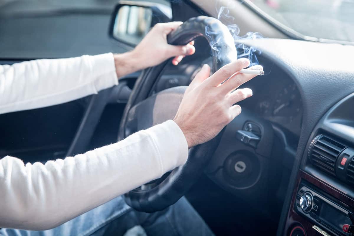 Man smoking a cigarette at the wheel of a car