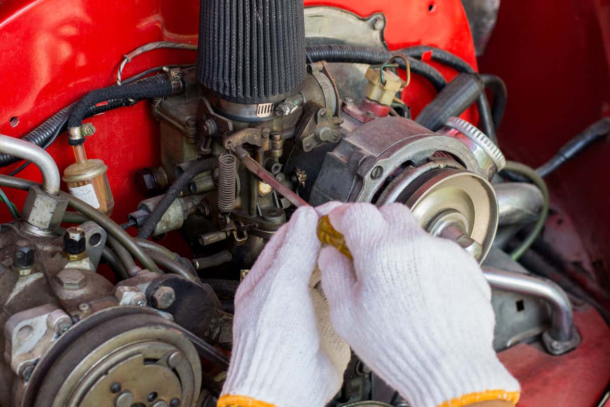 Mechanic man adjust the carburetor of the car at repair service station
