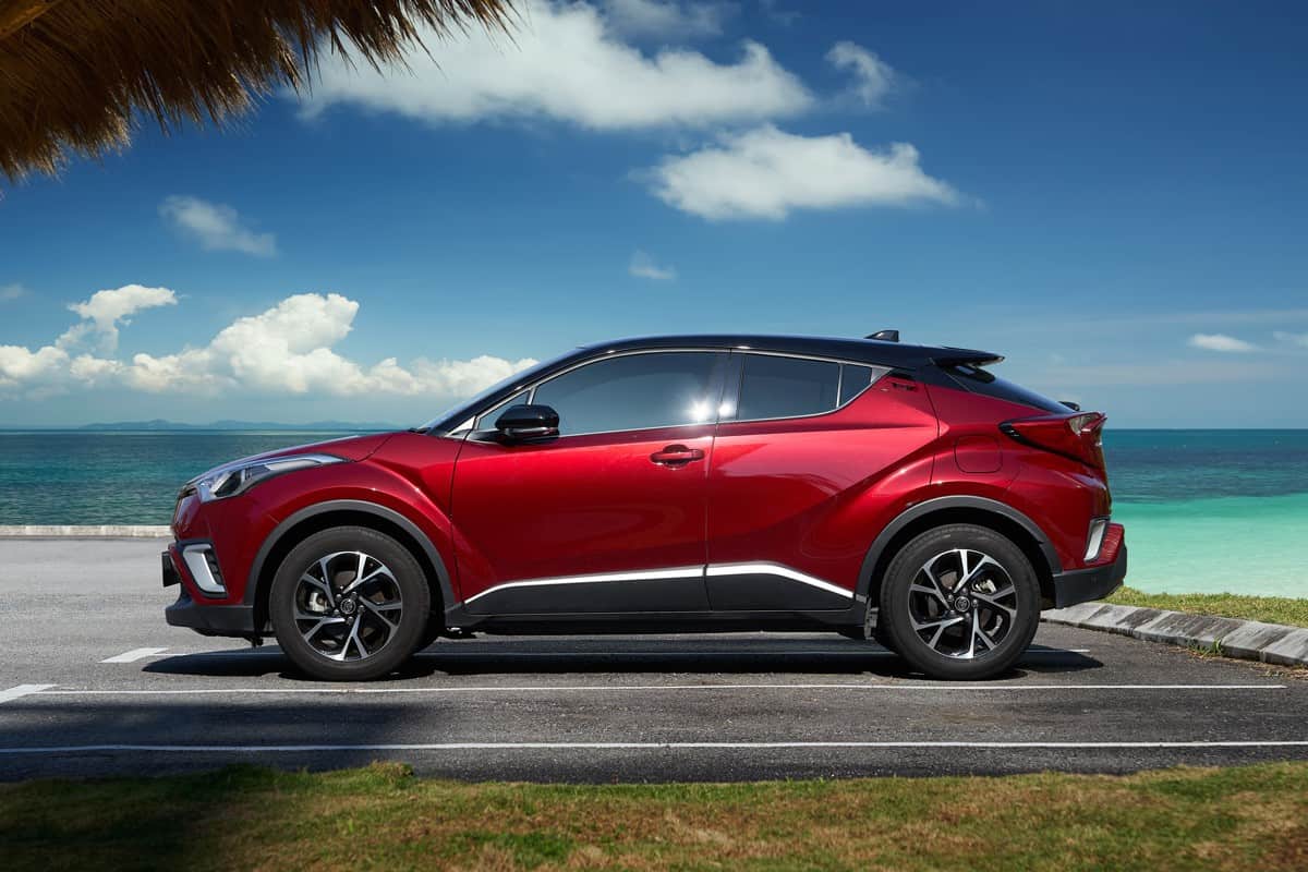 New red Toyota C-HR crossover SUV park at beach side .