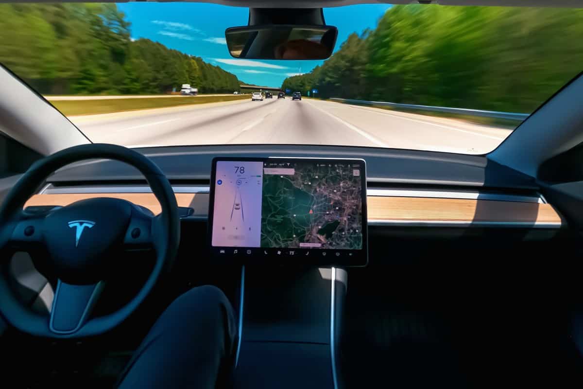 Person driving a new Tesla Model 3 on autopilot