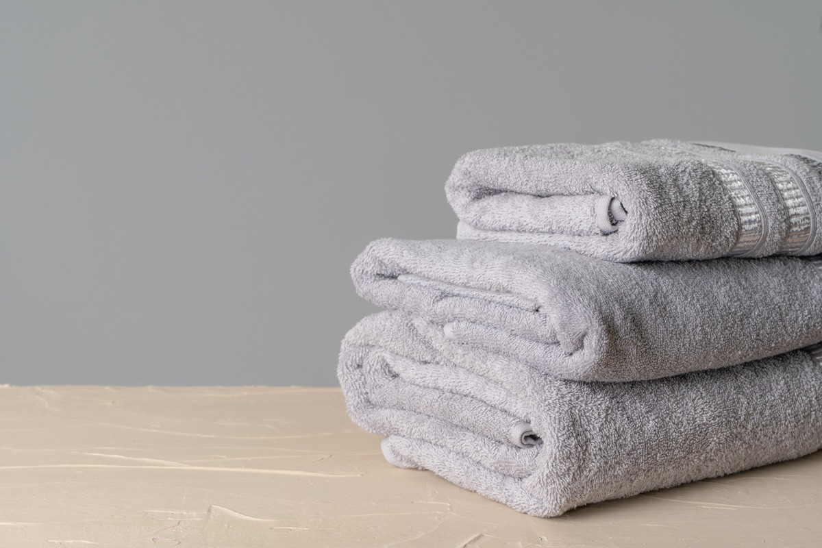Pile of clean new towels against grey wall